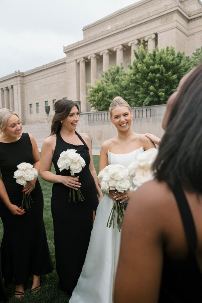 Wedding party laughing together on the museum lawn.
